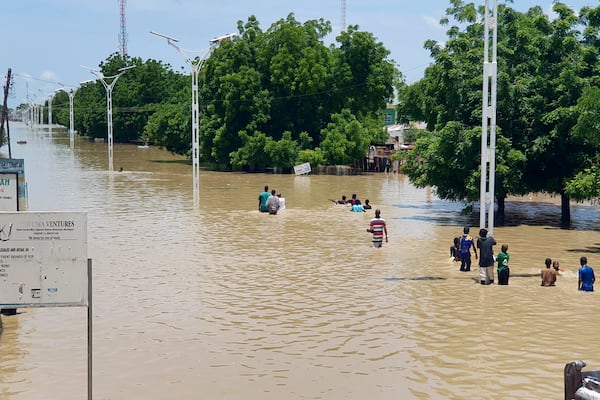 FILE - People walk through floodwaters following a dam collapse in Maiduguri, Nigeria Sept 10, 2024. (AP Photos/ Joshua Olatunji, File)