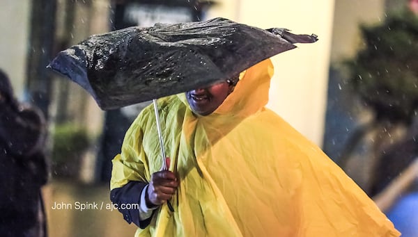 People on Marietta and Forsyth streets needed umbrellas early Tuesday as showers moved across metro Atlanta. JOHN SPINK / JSPINK@AJC.COM