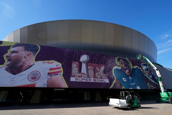 Workers hang Super Bowl banners outside the Caesars Superdome in New Orleans.