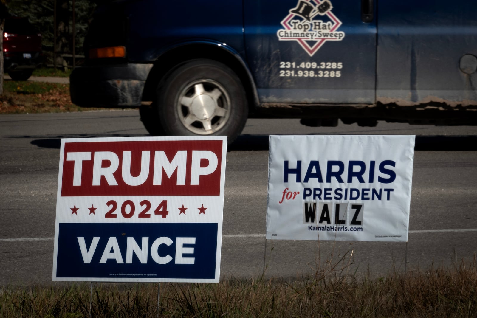 Election signs for Vice President Kamala Harris and former President Donald Trump are posted along a highway. 