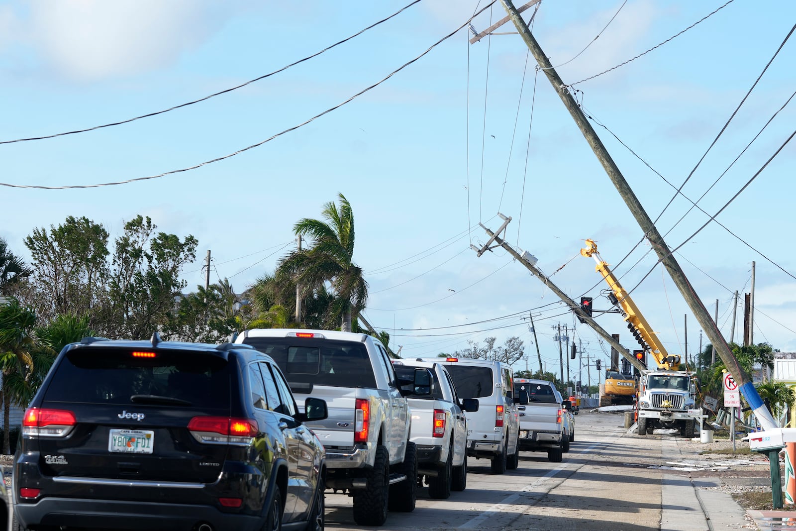 Cars move slowly in Matlacha, Florida, after Hurricane Milton damaged power lines.