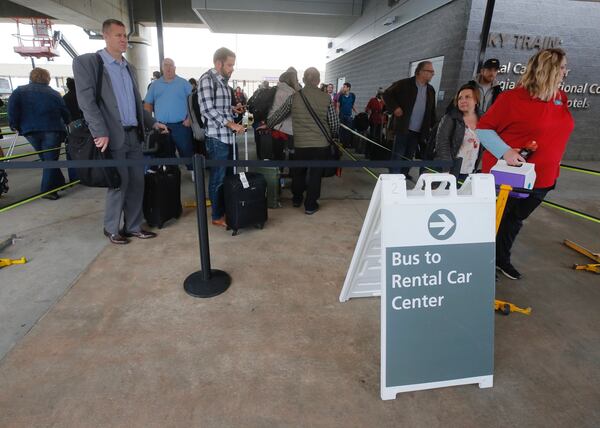 Travelers at Atlanta’s Hartsfield-Jackson International Airport wait to board shuttles to the rental car center on Monday, December 18, 2017. The SkyTrain between the airport and the center was now working Monday afternoon.