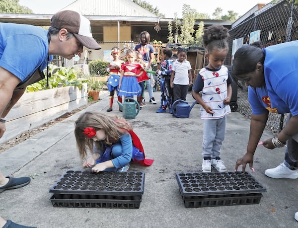 Germaine Appel (left), the school’s garden educator, and teacher Danielle Brown help kids plant seeds in the school garden. 