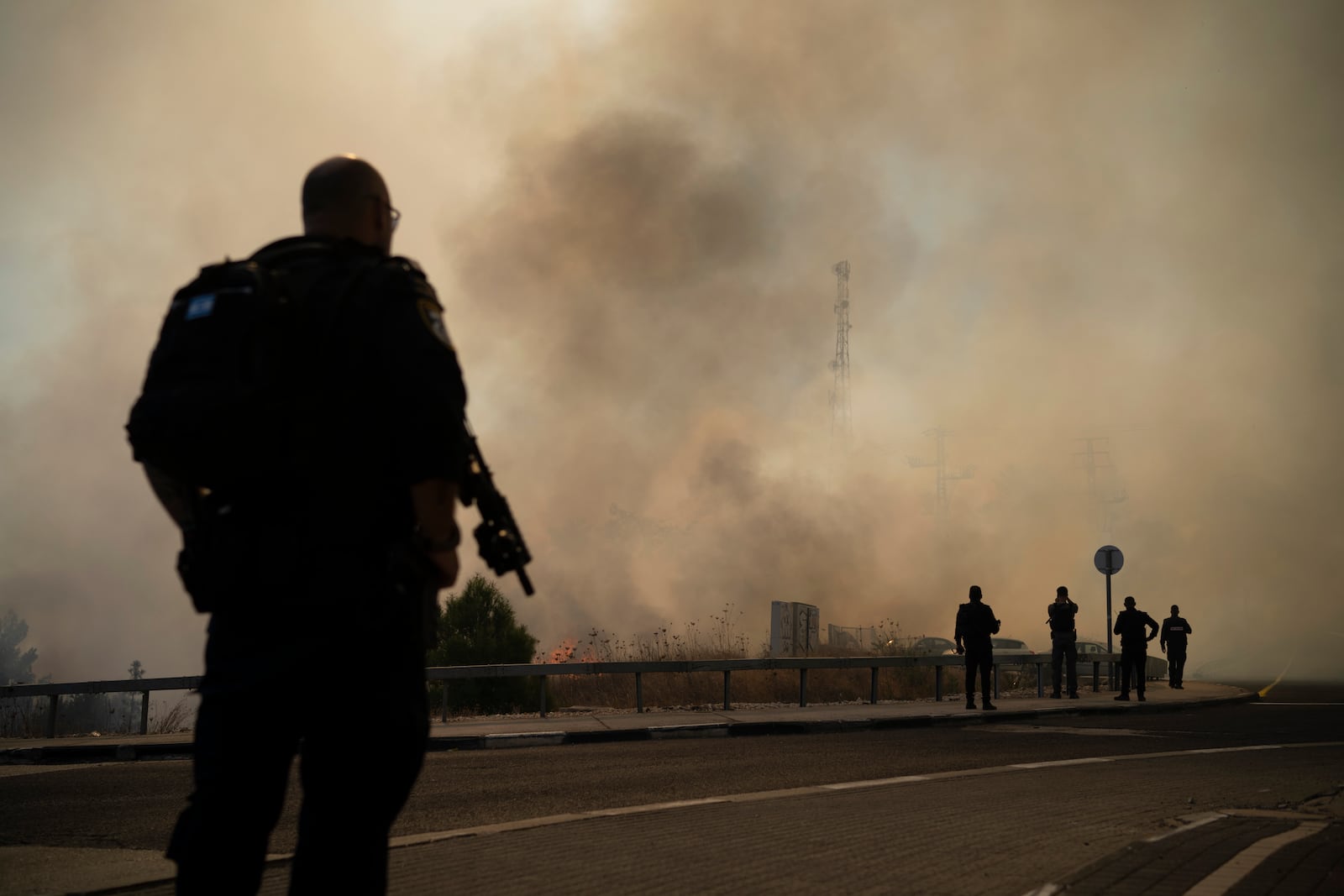 Israeli police officers stand next to a site of a fire after a rocket, fired from Lebanon, hit an area near the town of Rosh Pinna, northern Israel, Sunday, Oct. 20, 2024. (AP Photo/Leo Correa)