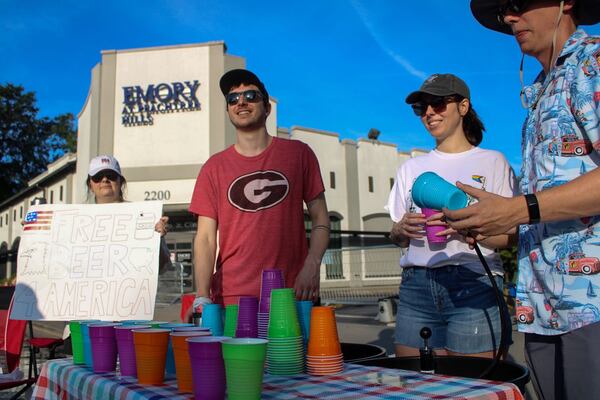 A group of spectators offer free beer to runners at the Atlanta Journal-Constitution Peachtree Road Race on Thursday July 4, 2024.