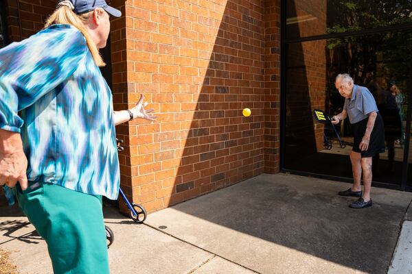 Frank Stovall practices hitting pickleballs with a friend outside the condo tower where Stovall lives. For years Stovall astounded people with his tennis skills, often besting younger competitors. He was still playing at 100. (Olivia Bowdoin for the AJC)