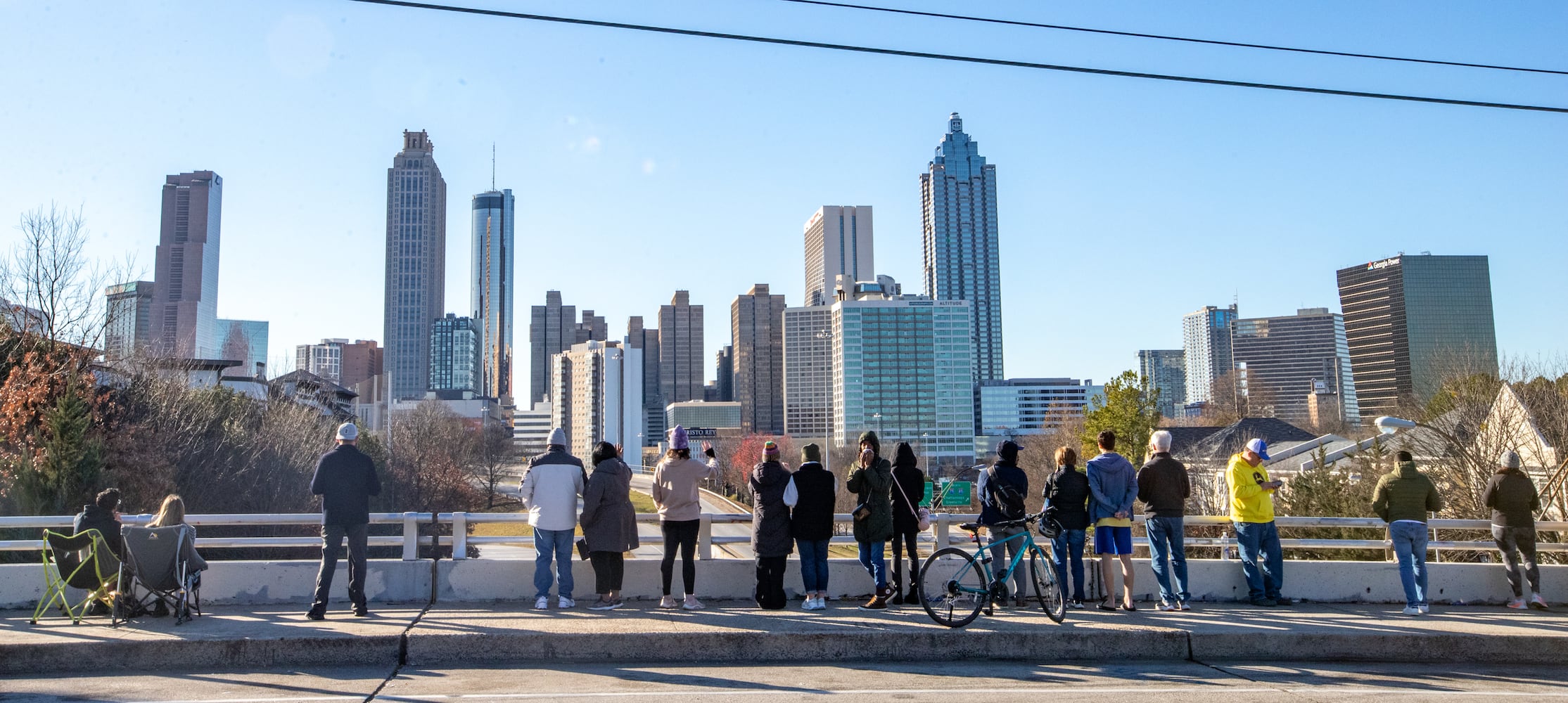 The Jimmy Carter motorcade proceeds from the Georgia Capitol to the Carter Center on Freedom Parkway on Saturday, Jan 4, 2025. Locals gather on the Jackson Street Bridge to pay respects as the motorcade passes. (Jenni Girtman for The Atlanta Journal-Constitution)