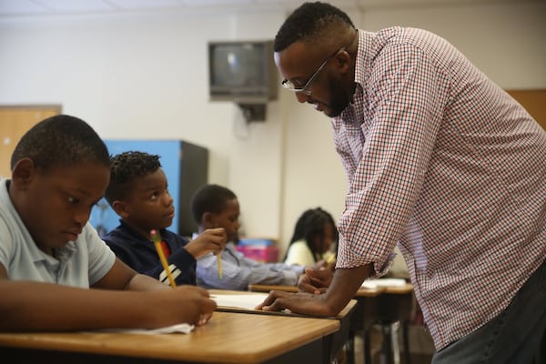 Fourth grade teacher Thaddeus Dawsey helps Jeremiah Jones (second from left) through an academic exercise at Gideons Elementary School. 