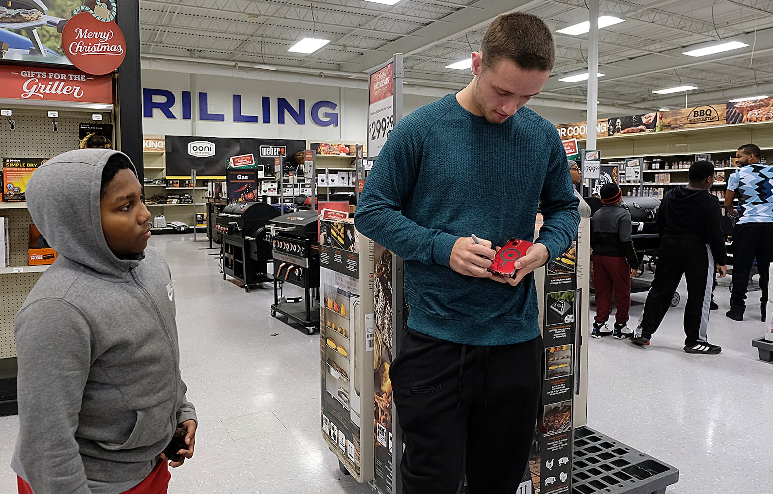 Davidian Colbert has his phone signed by UGA Quarterback Carson Beck who was on site at an Athen Academy store Sunday December 17, 2023, to give out gift cards to lucky members of area Boys and Girls Clubs. Academy Sports and Outdoors contributed $200 for each child and he kicked in $135 more of his own money to help families out. 

credit: Nell Carroll for the AJC