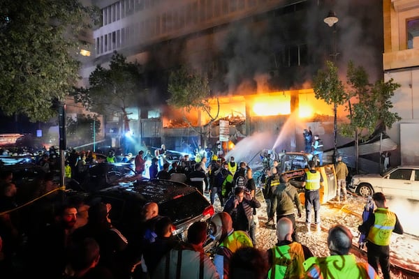 Civil defense workers extinguish a fire at the site of an Israeli airstrike in Beirut, Sunday, Nov. 17, 2024. (AP Photo/Hassan Ammar)