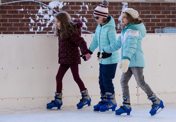 Alayna Lamorella, 10 (from left), Ashtyn Lovvorn, 10, and Adalyn Lamorella, 10, hold hands while making their way around the Have an Ice Day rink in downtown Sugar Hill on Saturday afternoon, December 26, 2020. (Photo: Ben Gray for The Atlanta Journal-Constitution)