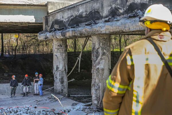 Atlanta firefighters remained on the scene putting out a smoldering fire Friday, March 31, 2017 at the I-85 collapse site while construction crews made their way into the zone to begin work. 