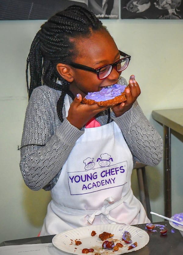 Toni Tomori, 7, of Nigeria delights in tasting her own version of an Oatmeal Cookie Crust dessert. Each student was given their choices of toppings and food colorings to create this dessert. CONTRIBUTED BY CHRIS HUNT PHOTOGRAPHY