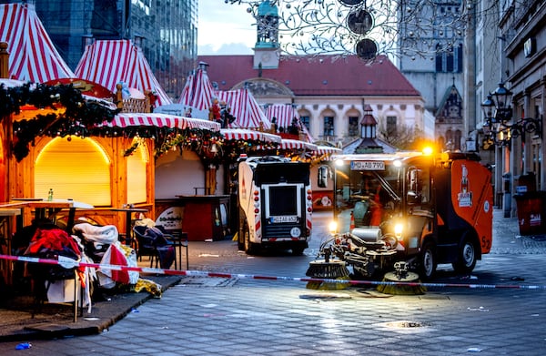 Public workers clean the Christmas Market, where a car drove into a crowd on Friday evening, in Magdeburg, Germany, is empty on Sunday morning , Dec. 22, 2024. (AP Photo/Michael Probst)