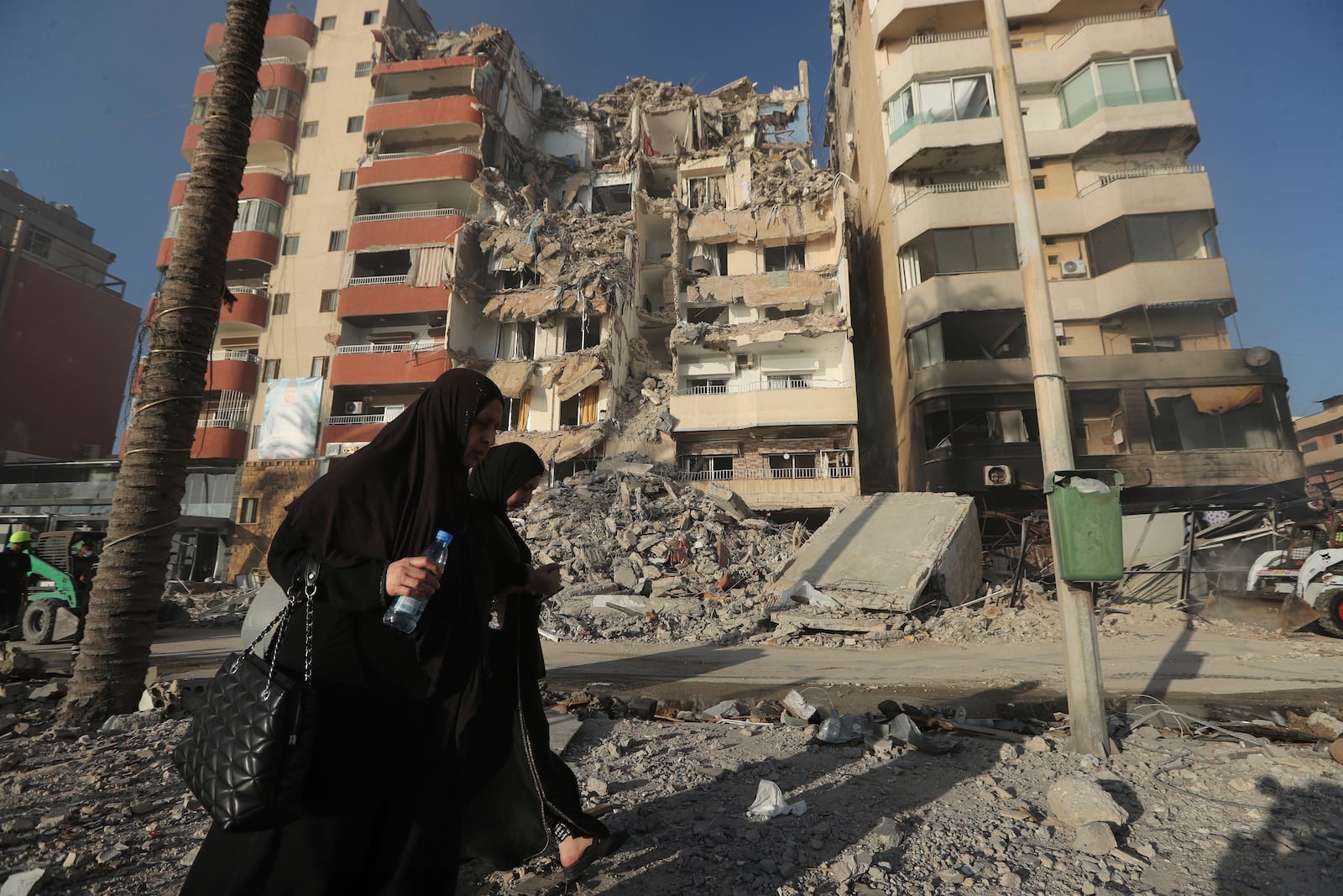 Lebanese women pass in front of a destroyed building hit in an Israeli airstrike in Tyre, Lebanon, Monday, Oct. 28, 2024.(AP Photo/Mohammed Zaatari)