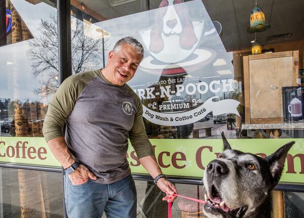 Joe Guerrisi and his 6-year-old Great Dane Chole are outside the coffee shop at the Perk-N-Pooch in Sandy Springs where dogs are bathed and groomed on Friday, March 14, 2021.  Guerrisi owns the business and has not had to close during the pandemic.  The coffee shop is closed to the public but dogs can be dropped off curbside for safe grooming and washing.  (Jenni Girtman for The Atlanta Journal-Constitution)