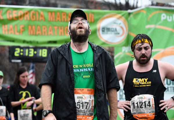 Publix Georgia Half Marathon runners Chris McKinney, of Marietta, Ga., (8517) and Robert Macedonia, of Atlanta, (11214) finish their race despite a steady rain on Sunday, March 22, 2015, in Atlanta. David Tulis / AJC Special