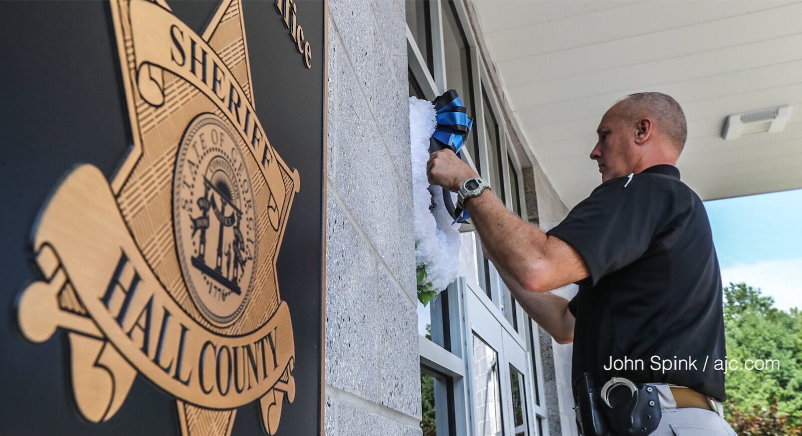 A Hall County sheriff’s deputy hangs a wreath following the shooting of 28-year-old Nicolas Dixon. AJC photo: John Spink