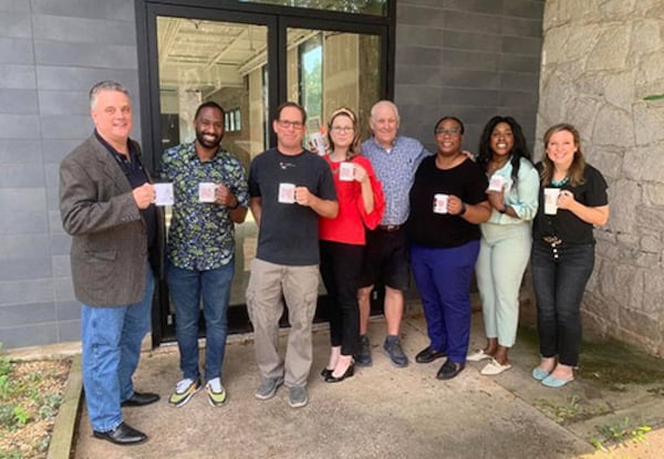 Steve Franklin (third from left), who co-owns JavaVino with his wife, Huddy Kuhl, poses in front of the Old Post Office building in Stone Mountain with members of the Stone Mountain Downtown Development Authority.