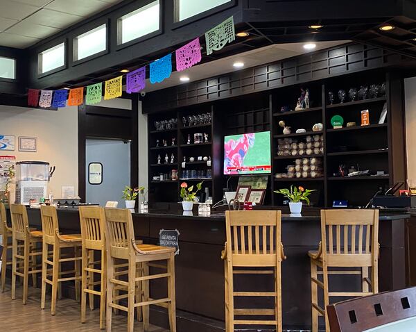 A colorful papel picado banner hangs above the bar at Birrieria Landeros. Ligaya Figueras/ligaya.figueras@ajc.com