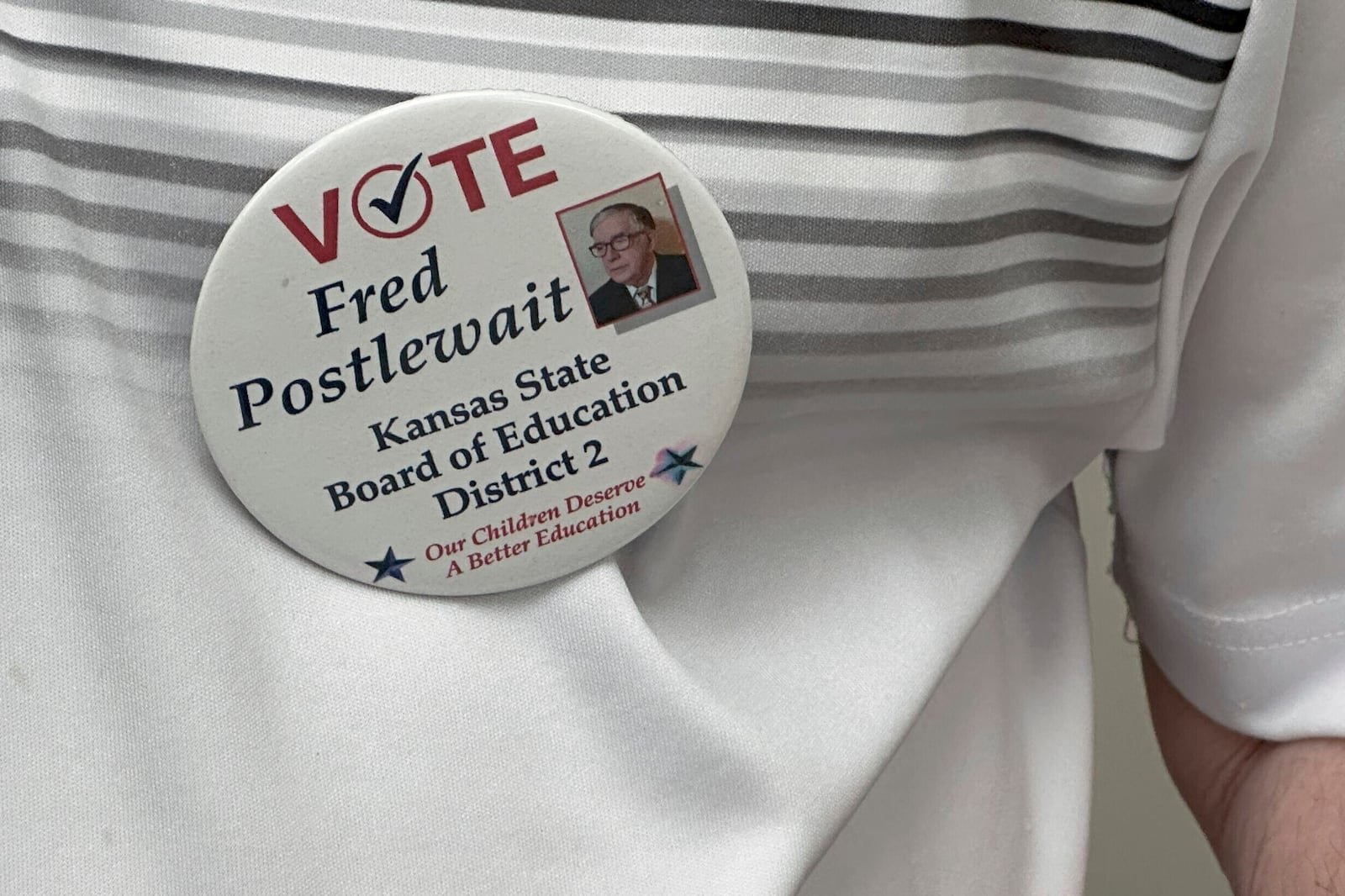 Fred Postlewait, a Republican candidate for the Kansas State Board of Education from Kansas City, wears one of his campaign buttons during an interview at the Johnson County Republican Party headquarters, Tuesday, Oct. 1, 2024, in Overland Park, Kan. (AP Photo/John Hanna)