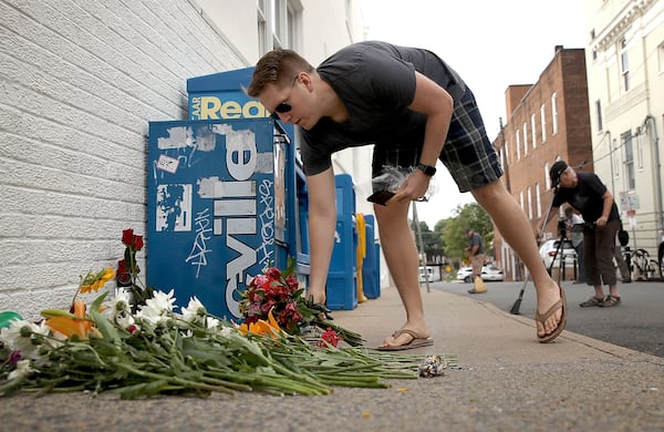 A man places flowers at a makeshift memorial Sunday for the victims of yesterday's attack where a car plowed into a crowd of demonstrators opposing a nearby white nationalist rally on Saturday in Charlottesville, Va.