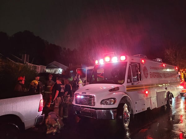 Gwinnett County firefighters gather in the rain outside the scene of a serious fire at the Montrose Berkeley Lake Apartments in Duluth.