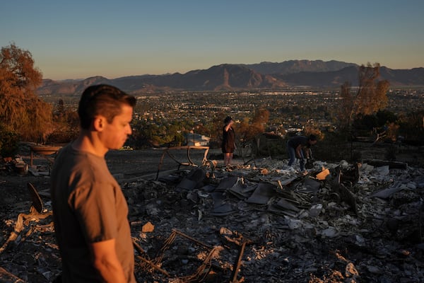 Louie Gonzalez, foreground, and his mother, Kathy, background center, visit Kathy's home devastated in the Mountain Fire in Camarillo, Calif., Nov. 8, 2024. (AP Photo/Jae C. Hong)