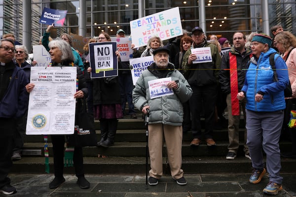 People hold signs as they gather outside the U.S. District Court after a federal judge blocked President Donald Trump's effort to halt the nation's refugee admissions system Tuesday, Feb. 25, 2025, in Seattle. (AP Photo/Ryan Sun)