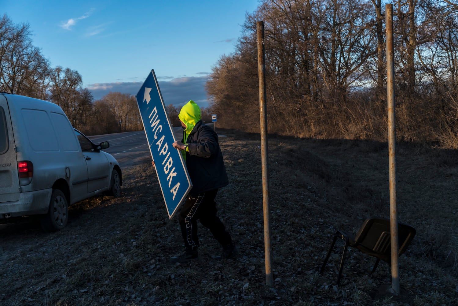 A Ukrainian worker removes a road sign to complicate Russian military navigation in Kalynivka, Ukraine, Feb. 26, 2022. (Brendan Hoffman/The New York Times)