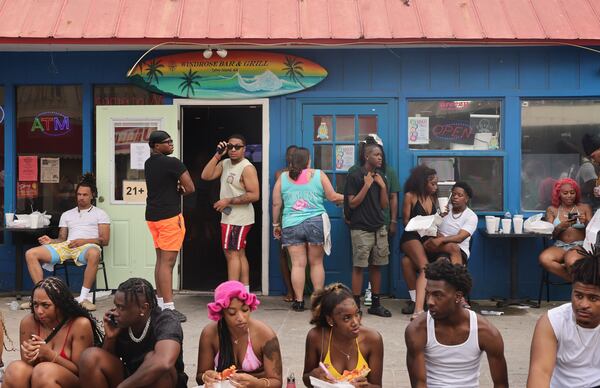 Orange Crush attendees relax and eat food on Tybrisa Street in Tybee Island on Saturday, April 20, 2024. (Natrice Miller/ AJC)