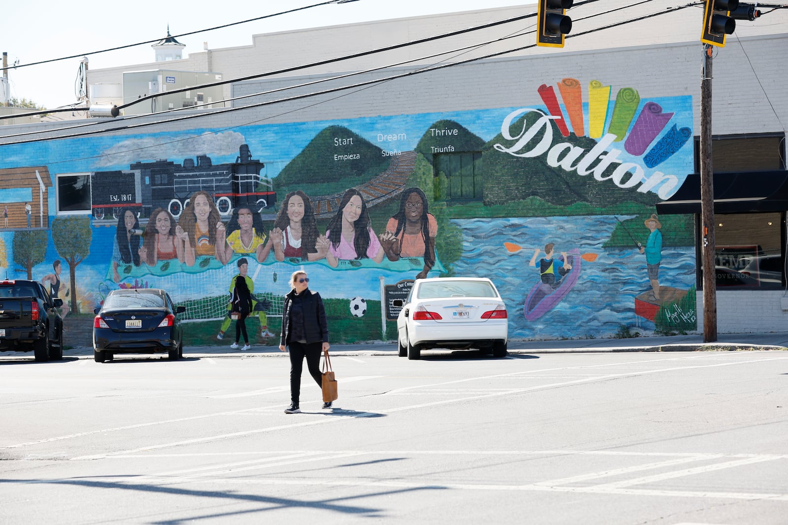 People walk crossing a mural painted by a Latina local artist Mayelli Medina at Oakwood Coffee shop in Downtown Dalton on Wednesday, October 19, 2022. The Hispanic presence is evident in the streets of Dalton, Georgia's largest majority-Hispanic town, with 51% of residents identifying as Latino per the 2020 census. Miguel Martinez / miguel.martinezjimenez@ajc.com