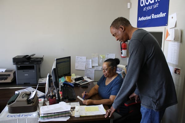 Cheryl Scott (seated) reviews an invoice with Morris Council, Jr., the business owner of MC&T Electronics in Tucker.