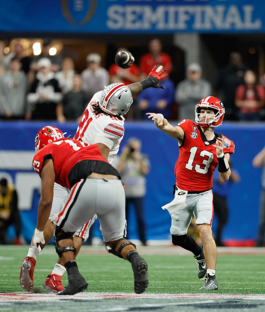 Georgia Bulldogs quarterback Stetson Bennett (13) throws under pressure during the fourth quarter of the College Football Playoff Semifinal between the Georgia Bulldogs and the Ohio State Buckeyes at the Chick-fil-A Peach Bowl In Atlanta on Saturday, Dec. 31, 2022.  Georgia won, 42-41. (Jason Getz / Jason.Getz@ajc.com)