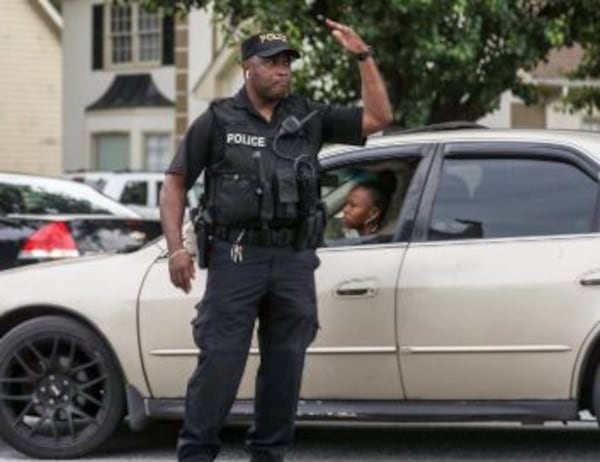 A DeKalb County Schools Police officer directs traffic into the parking lot of Wynbrooke Elementary School.