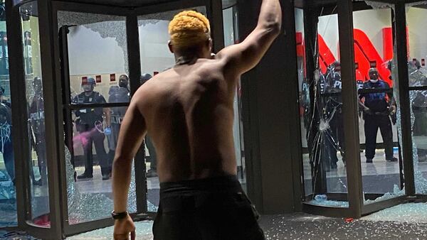 A man raised his fist in front of police officers who stood inside the CNN Center on Friday, May 29, 2020. He was among hundreds of demonstrators there to protest police misconduct, particularly the death of George Floyd, an African American man who died in police custody. Some demonstrators, though, looted several buildings in the area and vandalized the center. ERIC STIRGUS/ESTIRGUS@AJC.COM.