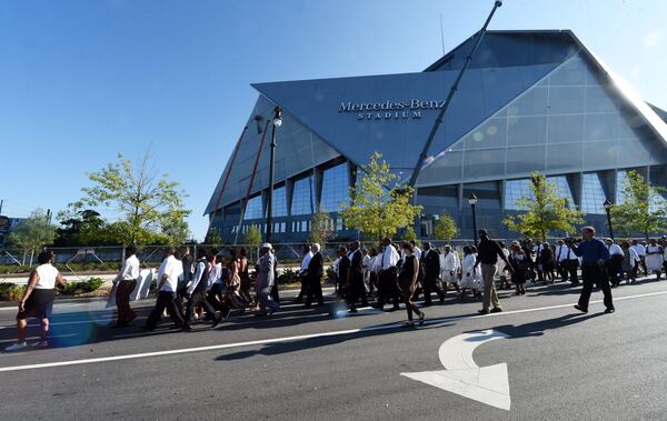 ATLANTA — With Mercedes-Benz Stadium in the background, members of Friendship Baptist Church march from Friendship’s old location before attending the first morning worship service at the church’s new site on July 30, 2017. The 155-year old historic church, which began as the home for both Morehouse and Spelman colleges, was rebuilt after its former edifice was demolished to make way for the stadium. (Kent D. Johnson / AJC file)