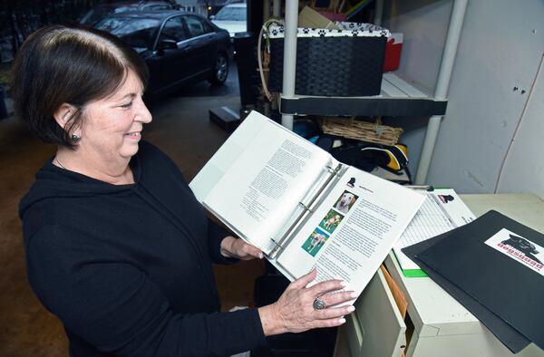 Toni Appling shows adoption files of dogs at her home in Johns Creek. She has saved hundreds of dogs as a dog rescuer and co-founder of the Atlanta Dog Squad, a group focusing on Labs and retrievers — large dogs. HYOSUB SHIN / HYOSUB.SHIN@AJC.COM