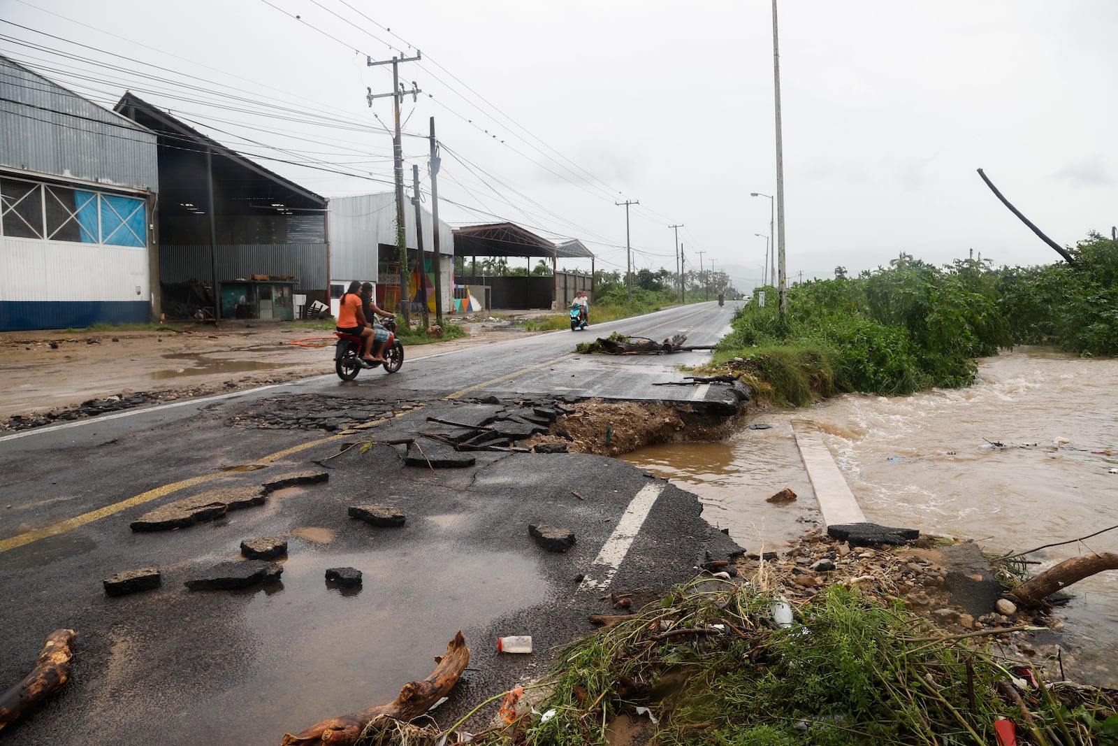 A motorcyclist rides by a street damaged during the passing of Hurricane John, in Acapulco, Mexico, Friday, Sept. 27, 2024. (AP Photo/Bernardino Hernandez)