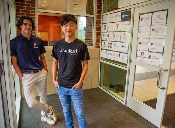 Atlanta International School seniors Rodrigo Villagomez (L) and George Song stand in a school entrance where seniors post paper signs with the logos of the colleges where they are going to attend. STEVE SCHAEFER FOR THE ATLANTA JOURNAL-CONSTITUTION