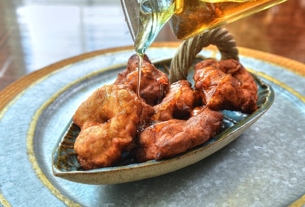 Bolivian Buñuelos, shown with honey, are a Christmas tradition in baker Lesly Sobel’s homeland. STYLING BY LESLY SOBEL / CONTRIBUTED BY CHRIS HUNT PHOTOGRAPHY