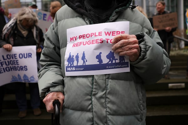 People hold signs as they gather outside the U.S. District Court after a federal judge blocked President Donald Trump's effort to halt the nation's refugee admissions system Tuesday, Feb. 25, 2025, in Seattle. (AP Photo/Ryan Sun)