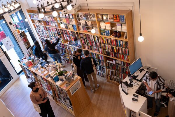 Yu Miao, right, owner of JF Books, looks at his phone as customers browse the books in his bookstore in Washington, Thursday, Oct. 3, 2024. (AP Photo/Ben Curtis)