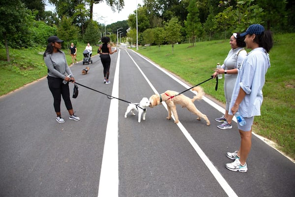 Crystal Betts (left) stops and talks with other dog owners while walking along one of the paths that runs through Westside Park on Friday, August 20, 2021. STEVE SCHAEFER FOR THE ATLANTA JOURNAL-CONSTITUTION