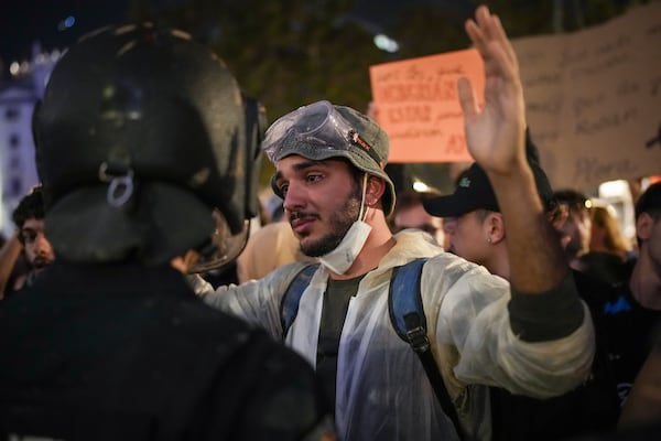 A demonstrator holds his hands up in front of riot police during a protest organized by social and civic groups, denouncing the handling of recent flooding under the slogan "Mazón, Resign," aimed at the president of the regional government Carlos Mazon, in Valencia, Spain, Saturday, Nov. 9, 2024. (AP Photo/Emilio Morenatti)