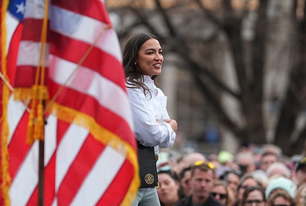 As Sen. Bernie Sanders, I.Vt., speaks, Rep. Alexandria Ocasio-Cortez, D-N.Y., greets well-wishers during a stop of the lawmakers' "Fighting Oligarchy" tour that filled Civic Center Park, Friday, March 21, 2025, in Denver. (AP Photo/David Zalubowski)