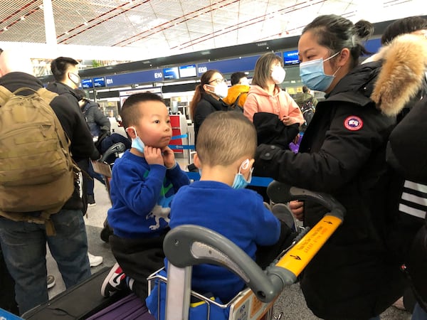 Children adjust their face masks as they wait in line at check-in counters at Beijing Capital International Airport on Saturday.