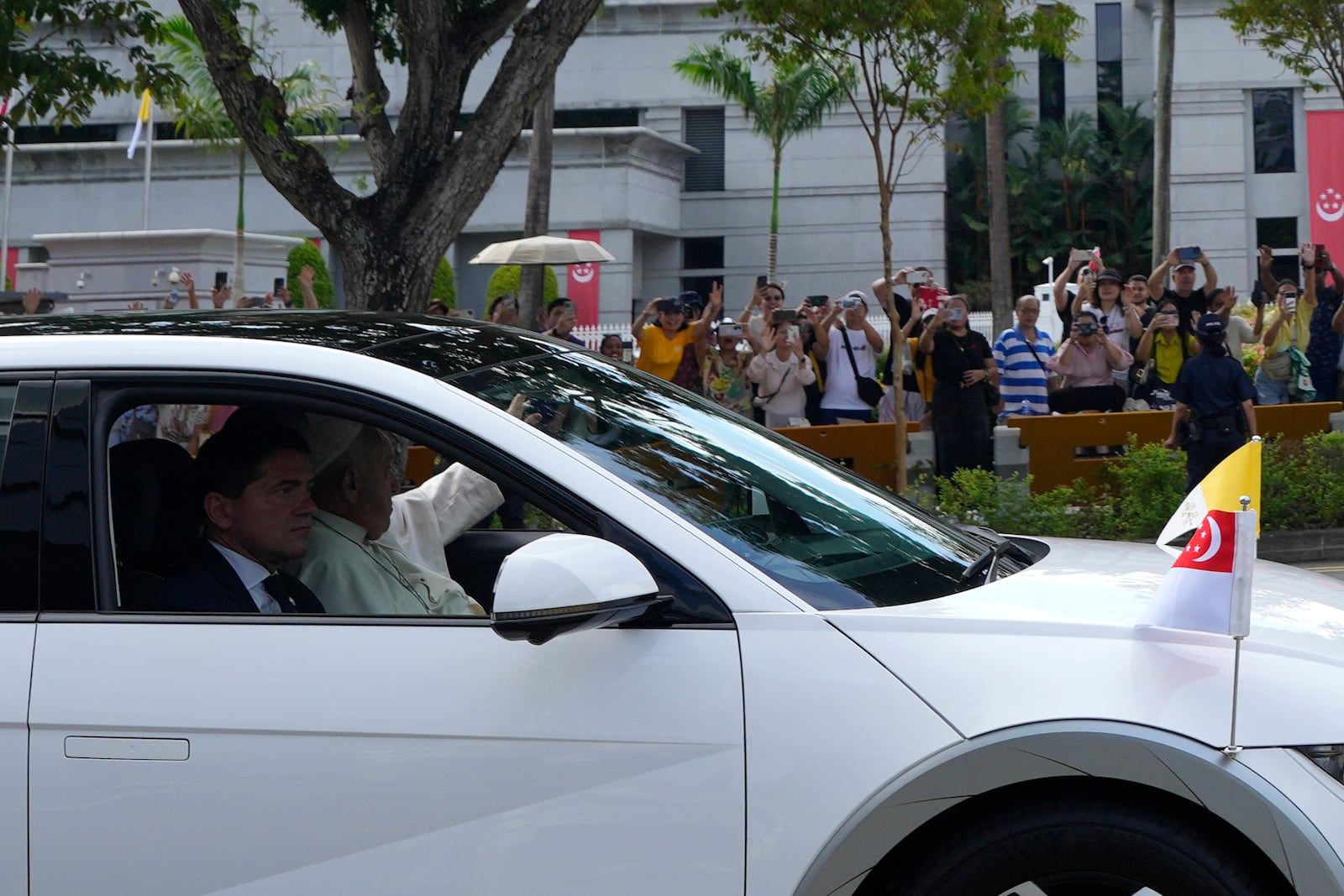 Pope Francis in a car, waves as he leaves from the Parliament House in Singapore, Thursday, Sept. 12, 2024. (AP Photo/Vincent Thian)