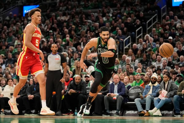 Boston Celtics' Jayson Tatum (0) runs by Atlanta Hawks' Dyson Daniels (5) while chasing the ball during the first half of an NBA basketball game, Saturday, Jan. 18, 2025, in Boston. (AP Photo/Robert F. Bukaty)