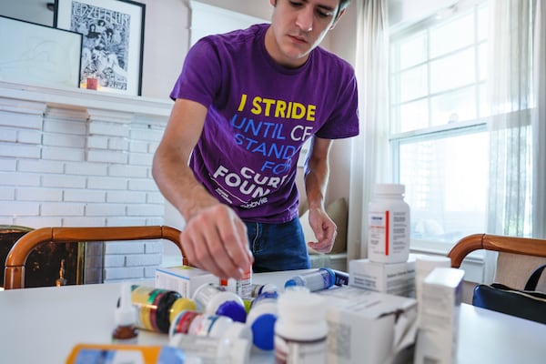 Tom Kerekes sorts through multiple medications and vitamins that he takes every day to deal with cystic fibrosis. While there's no true cure yet, Kerekes says that he's hopeful for many children who have the disease. “They will never have to go through the dark ages,” he says. (Natrice Miller/natrice.miller@ajc.com)  